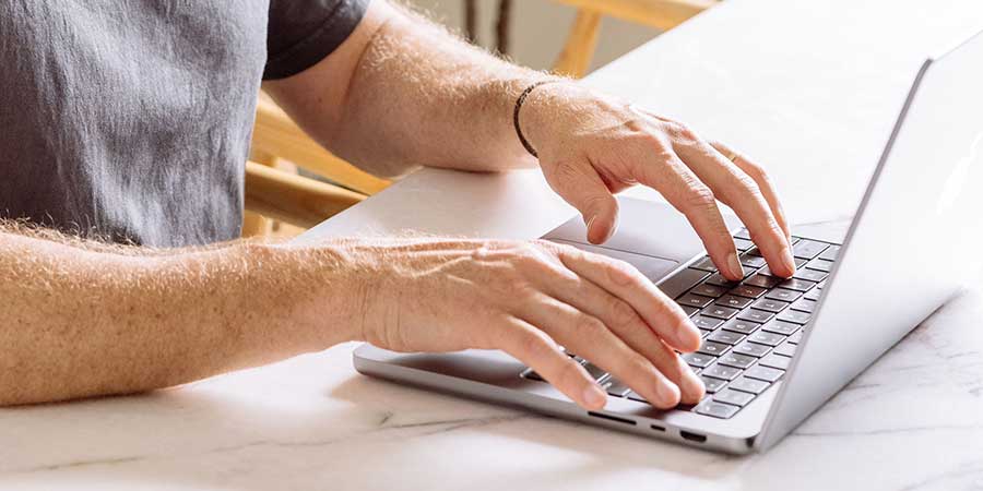 man typing on his computer.